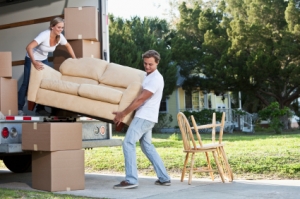 Two people unloading a sofa from a van